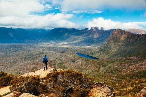 A hiker on the way up Mt Ossa high above Pinestone Valley with the Du Cane Range in the background. - Australian Stock Image