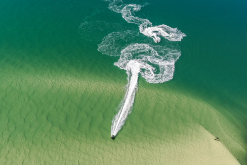 A jet ski sweeping across the calm turquoise waters of Wallis Lake in Forster - Australian Stock Image