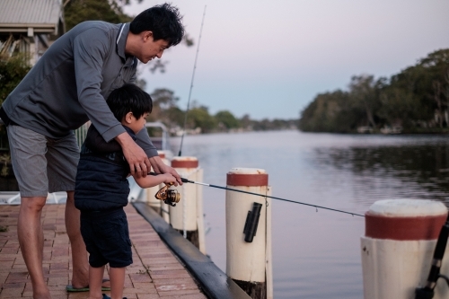 a kid being taught how to fish - Australian Stock Image