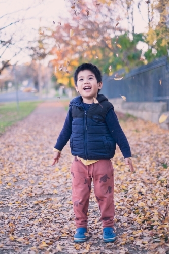a kid having some fun with autumn leaves