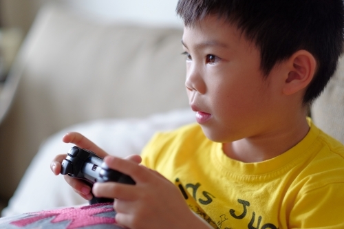 a kid, playing a console game in the living room