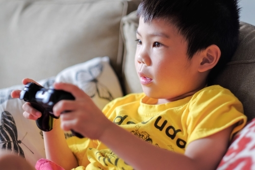 a kid, playing a console game in the living room - Australian Stock Image