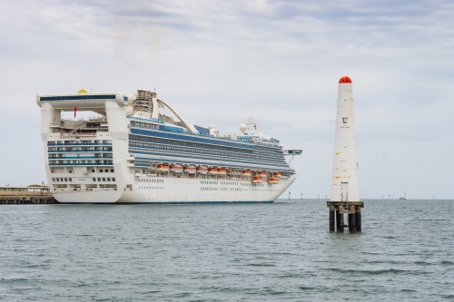 A large cruise ship docked near a signal beacon - Australian Stock Image