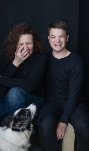 A laughing mother and her teenage son with her black and white dog - Australian Stock Image
