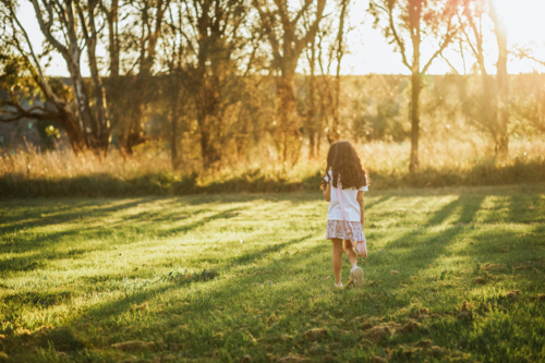 A little girl walking in the park during sunset - Australian Stock Image