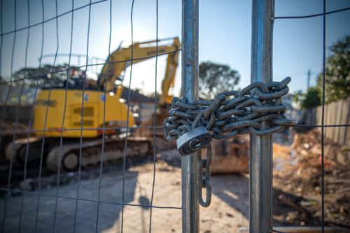 A locked gate with chain at a construction site with machinery in the background - Australian Stock Image
