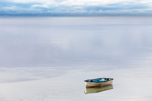 A lone dinghy tied up on still water