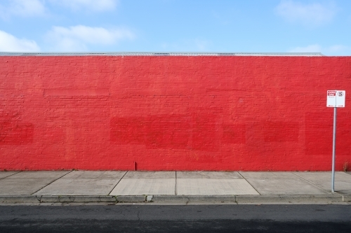 A long red wall with a street sign in front of it - Australian Stock Image