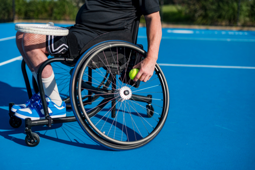 A male athlete in a wheelchair getting a tennis ball from the wheelchair - Australian Stock Image