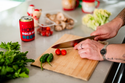 A man cutting tomatoes in kitchen at christmas - Australian Stock Image