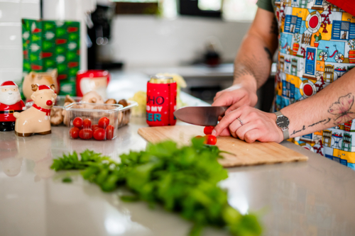 A man in an apron cutting tomatoes in kitchen - Australian Stock Image