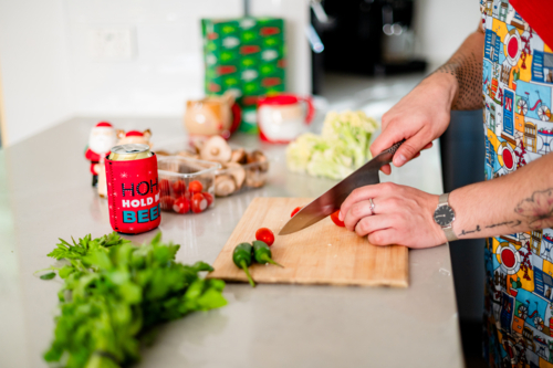 A man in an apron cutting tomatoes in kitchen - Australian Stock Image