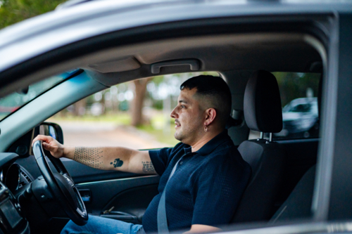 A man in his 30s drives through a peaceful park, enjoying the warm outdoors - Australian Stock Image