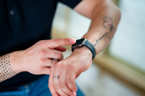 A man in his 30s is using a smart watch at home, checking information on the device - Australian Stock Image