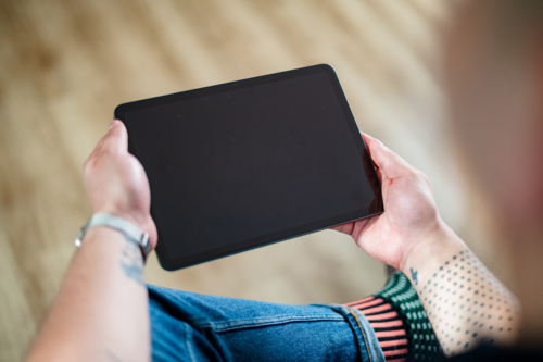 A man in his 30s, wearing a smartwatch, sits comfortably and interacts with a tablet at home - Australian Stock Image
