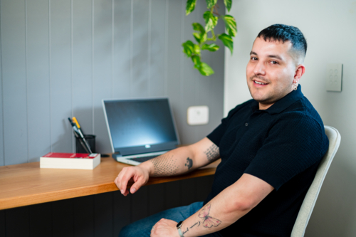 A man in his 30s, working from a comfortable home office with a laptop - Australian Stock Image