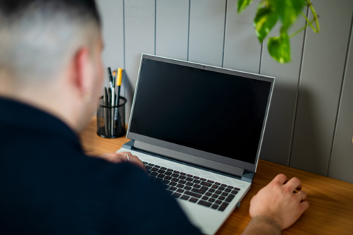 A man in his 30s working on his laptop at home - Australian Stock Image