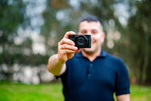 A man in his thirties smiles while taking a picture in a park during daylight - Australian Stock Image