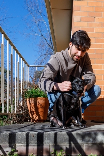 A man on his porch about to take his dog for a walk - Australian Stock Image