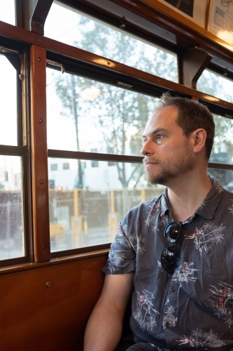 A man sitting in a famous historic Melbourne W Class tram looking out the window - Australian Stock Image