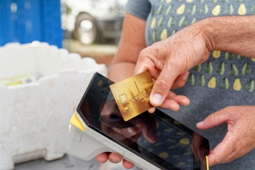 A man using technology making a mobile eftpos payment with a credit card - Australian Stock Image