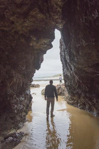 A man walks through a cave on the beach