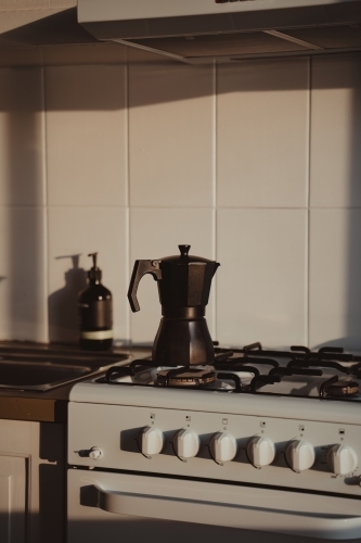 A matte black Moka Pot on a stove in the morning light. - Australian Stock Image
