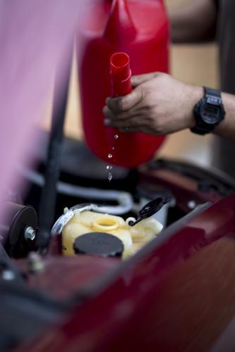 A mechanic refills windscreen washer fluid.