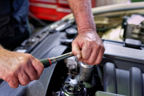 A mechanic servicing a luxury car in his workshop on the Gold Coast - Australian Stock Image