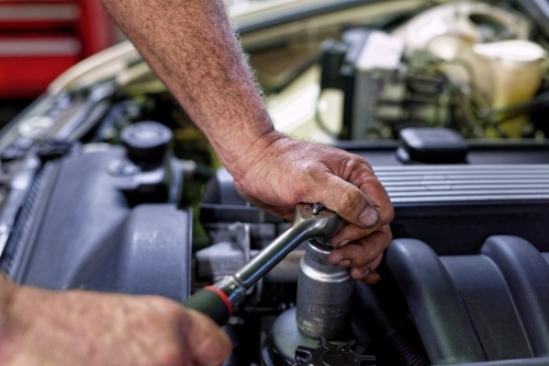 A mechanic servicing a luxury car in his workshop on the Gold Coast - Australian Stock Image