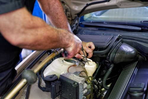 A mechanic servicing a luxury car in his workshop on the Gold Coast - Australian Stock Image