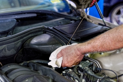 A mechanic servicing a luxury car in his workshop on the Gold Coast - Australian Stock Image