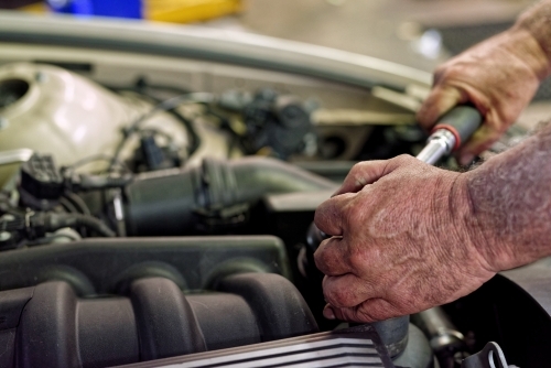 A mechanic servicing a luxury car in his workshop on the Gold Coast - Australian Stock Image