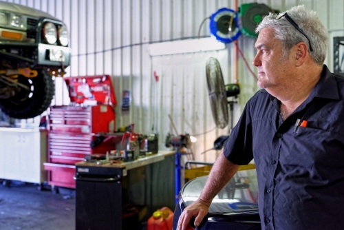 A mechanic standing in his workshop on the Gold Coast looking out - Australian Stock Image