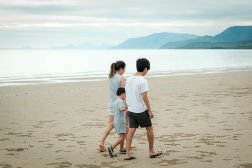 a mother and her kids walking along the beach