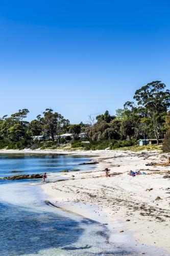 A mother and kids play on the beach in a sheltered cove - Australian Stock Image