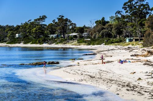 A mother and kids play on the beach in a sheltered cove