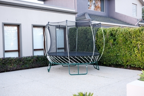 A new trampoline sits in the driveway of a modern home