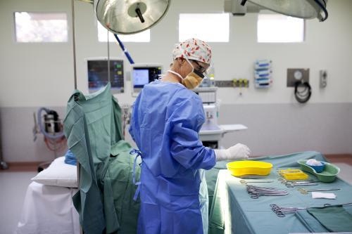 A nurse in a hospital operating theatre with table of surgical equipment - Australian Stock Image