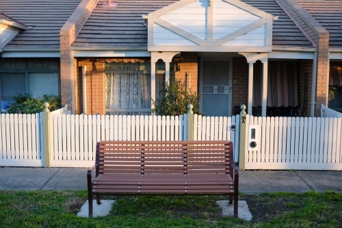 A park bench installed on the nature strip front of a row of houses - Australian Stock Image