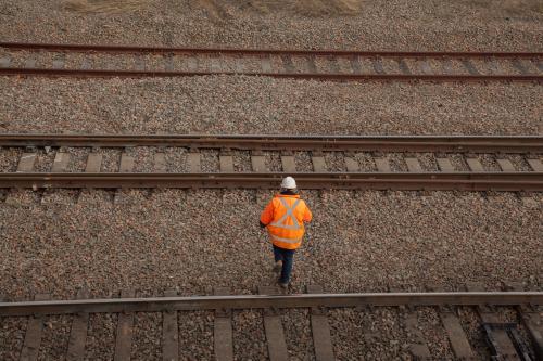 A person walking over three train tracks from overhead - Australian Stock Image
