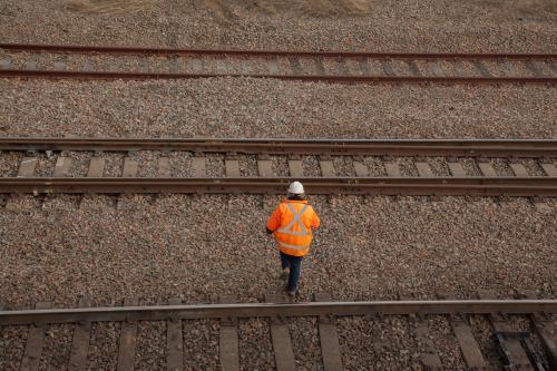 A person walking over three train tracks from overhead