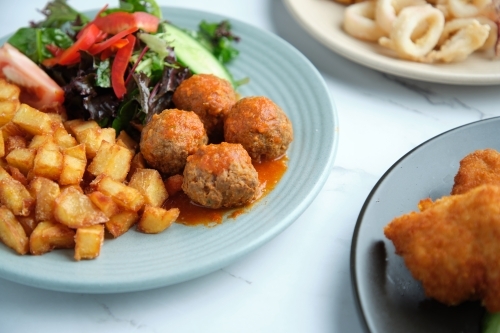 A plate of diced potatoes, salad and meat balls. - Australian Stock Image