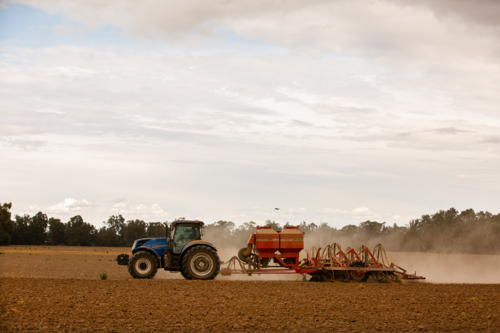 A ploughed paddock being sown with a tractor and seeder for cereal grain - Australian Stock Image
