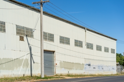 A power pole outside the door of a large corrugated iron warehouse - Australian Stock Image