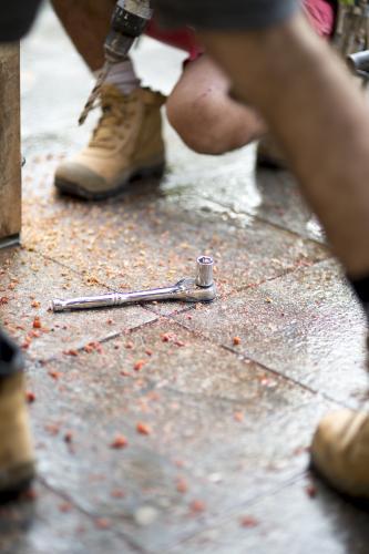 A ratchet and socket lies between two tradesmen on a home renovation site.
