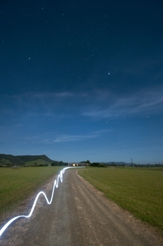 A ribbon of torchlight along a farm road at night