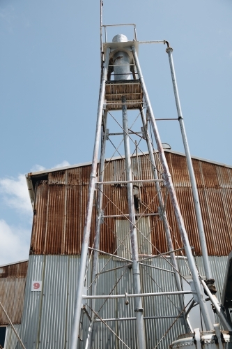 A rusted water tower with a building made of rusted corrugated metals in Old Whaling Station - Australian Stock Image