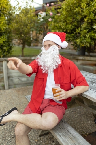 A Santa Claus at Christmas time in  the Australian summer holding a beer - Australian Stock Image