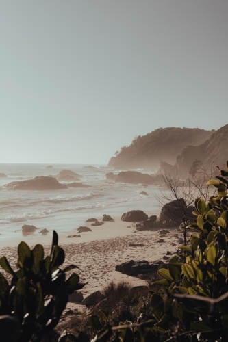 A secluded, rocky beach on a hazy morning after sunrise. - Australian Stock Image